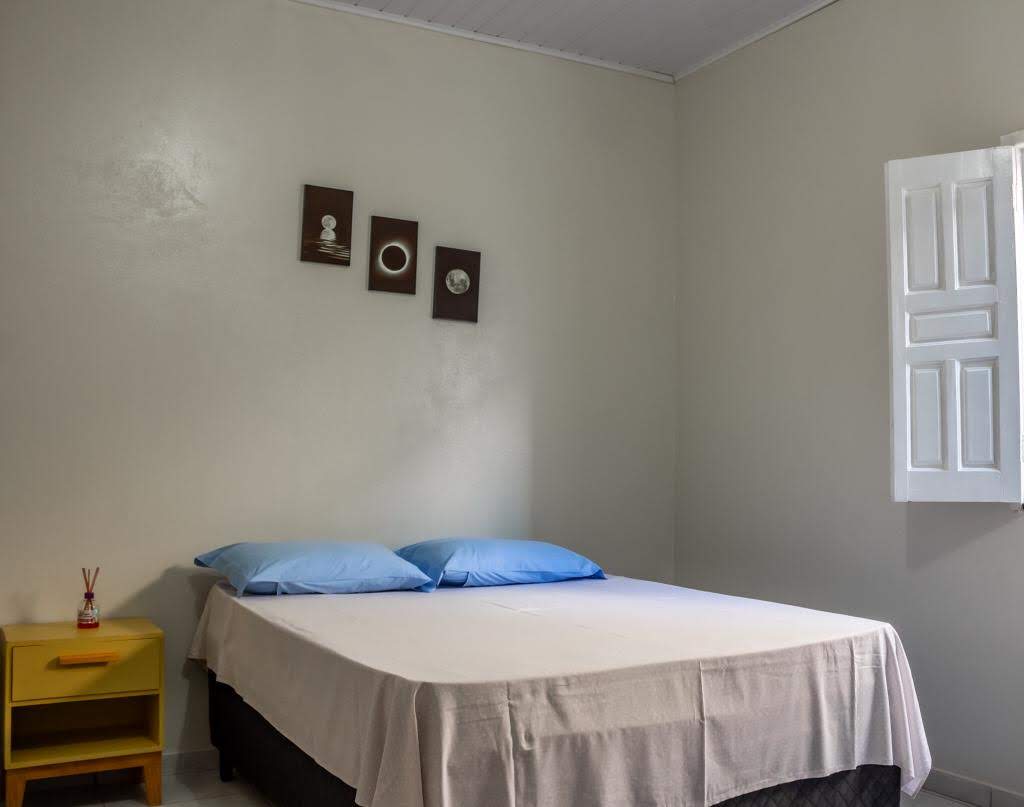 Acomodação espaçosa da Casa Amarela com cama de casal e beliche em Alcobaça-BA
